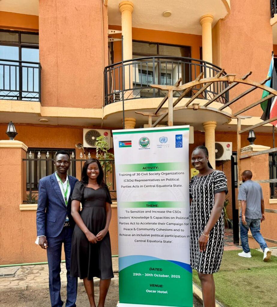A small number of participants posing for a photo with the poster outside the training hall